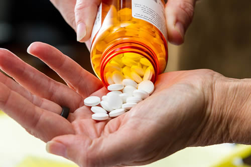 Close up of a hand handling prescriptions pills.
