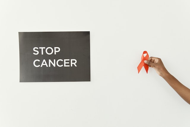 Advocate holding an Cancer Ribbon and sign that reads Stop Cancer. 