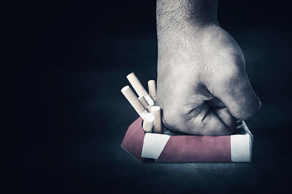 man's hand punching a pack of cigarettes